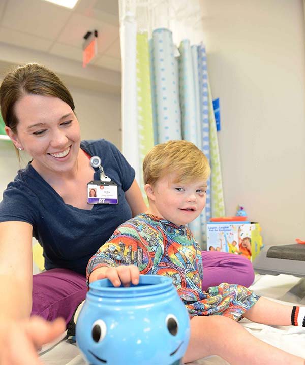 Nurse playing with child holding blue toy.