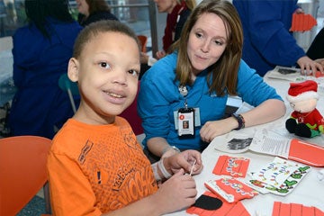 Nurse helping boy with arts and crafts.
